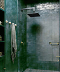 Matte black rain shower with 12-inch square solid brass arm, anti-scratch O-ring flange in modern green tiled bathroom.