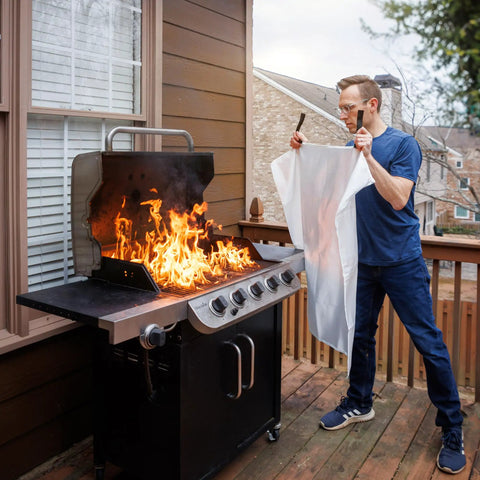 Person using Emergency Fire Blanket 40 By 40 Inches, Woven Fiberglass Fire Shield for smothering grill fire, outdoor safety.