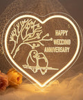 Heart-shaped LED sign with 'Happy Wedding Anniversary' glowing neon, birds on branch, romantic decor