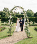 Iron Pergola Garden Arbor For Weddings And Backyards, 7.9 Feet High By 4.6 Feet Wide, arch adorned with flowers and ribbons