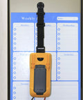 Magnetic Hanger Kit For Fluke Multimeters With Strap And Clip holding tool on a metal surface in front of a weekly planner.