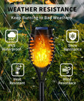 Lit Outdoor Solar Torch Lights Flickering Flame showing weather resistance, illuminating beside green foliage.