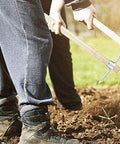 Person using Heavy Duty Stainless Steel Double Headed Pickaxe With Wooden Handle For Garden And Landscaping A True Yard Workhorse