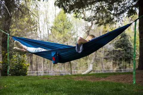 Person relaxing in Ultralight Camping Hammock 12 Oz Lightweight Blue Portable Ripstop Polyester 96 By 46 Inch Solo Lounger outdoors