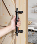 9 Inch Barn Door Pull Handle Set In Rustic Black Aluminum with ergonomic chamfered edges being held on a wooden door.