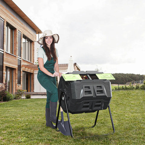 Woman using Two Chamber Outdoor Compost Tumbler Bin With Built In Thermometer For Easy Temperature Monitoring, Rotates Smoothly On Sturdy Steel Frame, 43 Gallon Capacity Split Into 2 X 21.5 Gal Compartments, Green Door in garden