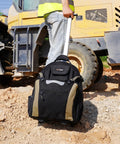 Person transporting Rugged Rolling Tool Backpack With Wheels 26 Pocket Organizer For Electricians Carpenters HVAC And Welders Built To Last In Durable 600D Polyester Worksite Ready On The Go on a construction site