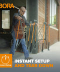 Man carrying unfolded Beefy Folding Work Table Centipede Saw Horse Stand 2 ft long by 4 ft wide by 2.5 ft high steel 1500 lb capacity