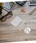Wooden table with All In One Eyeglasses Repair Kit With Silicone Nose Pads, Mini Screwdrivers, Tweezers And Tiny Screws, next to glasses.