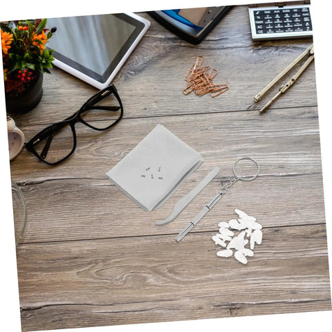 Wooden table with All In One Eyeglasses Repair Kit With Silicone Nose Pads, Mini Screwdrivers, Tweezers And Tiny Screws, next to glasses.