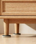Close-up of heavy duty furniture sliders under a wooden cabinet, showing 3.5 inch plastic movers on tile floor.