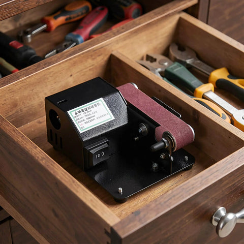 Compact Mini Electric Belt Sander With A Kickass Motor For Handheld Wood Sanding And Fast Metal Polishing Quick Rust Removal And Smooth DIY Finishes Built Like A Rock Solid Workhorse inside a workshop drawer.