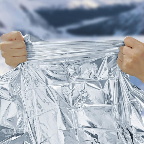 Hands pulling Mylar Emergency Blankets Space Blanket Thermal Survival Gear For Camping And Outdoors Hiking Bug Out Bags And First Aid Kits