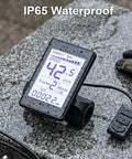 Waterproof Dope Electric Bike LCD Display Meter With 5 Pin Connector showing speed and trip distance on wet surface.