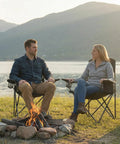 Two people sitting on Heavy Duty Folding Chairs With Built In 4 Can Cooler Bag And Cup Holders, 250 Lbs Capacity, 2 Pack by a lake