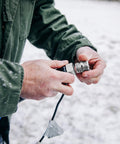 Camco 25-ft heated RV water hose connector, close-up of hands attaching in snow; metal threaded ends visible