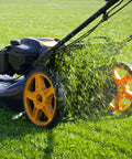 Lawn mower side view; black body with orange wheels cutting green grass.