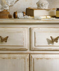 Butterfly drawer pulls on a distressed white dresser; part of 2 Pack Butterfly Cabinet Knobs In Gold Pewter With Delicate Wings.