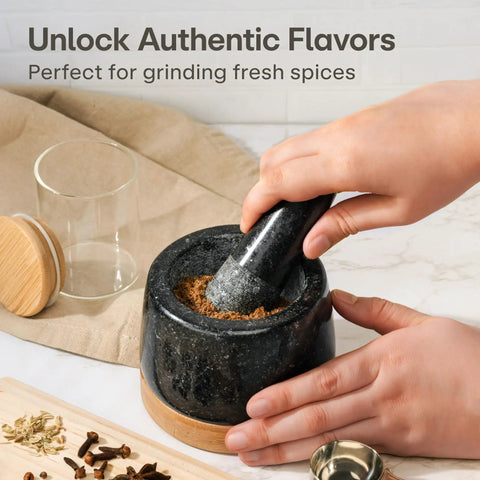 Hands using Heavy Duty 1 Cup Granite Mortar And Pestle Set For Spices And Herbs Molcajete Style Stone Grinder With Non Slip Wooden Base.