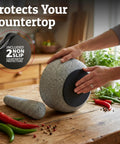 Heavy Duty Granite Mortar And Pestle Set Hand Carved From Natural Stone Two Cup Grinder Bowl For Fresh Guacamole Salsa Pesto Herbs And Spices Six Point Three Inches Wide Grey Great For Grinding Spices Seeds And Seasonings on kitchen counter with non-slip protectors