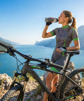 Woman drinking water next to bike equipped with 7 Speed Twist Shifter Lever For MTB And Folding Bikes With Ergonomic Grip And Crisp Shifts.