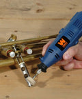 Front view of blue WEN rotary tool with flex shaft, hand-held, grinding a brass tube and fittings.