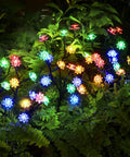 Solar Garden Lights Outdoor Decorative Six Pack Multicolor LED Flower Stakes glowing in garden foliage at night.