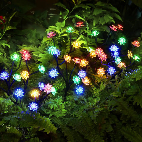 Solar Garden Lights Outdoor Decorative Six Pack Multicolor LED Flower Stakes glowing in garden foliage at night.