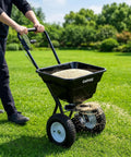 Person using 80 Lb Capacity Push Broadcast Spreader With 12 Ft Spread Width And 13 In All Terrain Wheels Adjustable Flow Control Heavy Duty Walk Behind Lawn Spreader For Fertilizer Grass Seed Ice Melt And Salt on grass