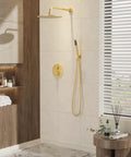 Wall-mounted gold shower system with rain shower head and handheld sprayer in modern bathroom with decorative accents and tiled walls.