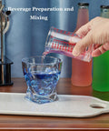Pouring liquid from Glass Shot Measuring Cup 4oz for Cocktails and Espresso into glass on wooden countertop