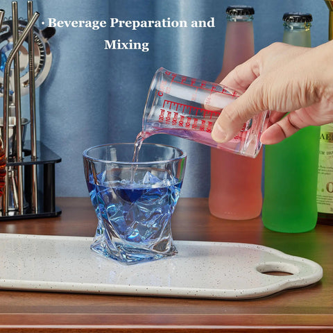 Pouring liquid from Glass Shot Measuring Cup 4oz for Cocktails and Espresso into glass on wooden countertop