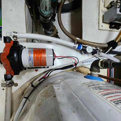 12V RV Water Pump 5.5 GPM 60 PSI Heavy Duty Diaphragm Pump installed with pipes and electrical connections in a boat.
