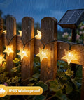 Solar Star String Lights 39Ft Outdoor Waterproof Fairy Lights with 100 LEDs on a wet wooden fence at night, IP65 rating visible