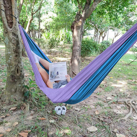 Person relaxing in a 400 Lb Capacity Portable Camping Hammock With Quick Setup Under 3 Minutes, Heavy Duty 210D Nylon Taffeta, 103 Inch Long By 55 Inch Wide