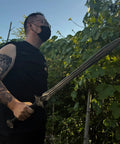 Person holding Hand Forged Knight Sword in Spring Steel 35 Inch Full Tang Medieval Blade outdoors near greenery