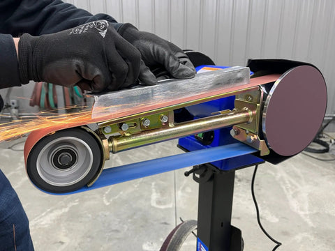Level Up Your Garage Operation With This Hardcore One Horsepower Belt Sander And Bench Grinder Combo showing grinding action on a metal piece.