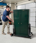 Man using Anderson Dolly Adjustable Heavy Duty Moving System with a green cabinet for easy maneuvering.