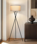LED Floor Lamp Tall Tripod With Drum Shade In Black Finish And Gold Accents, next to a cabinet in a modern living room setting.