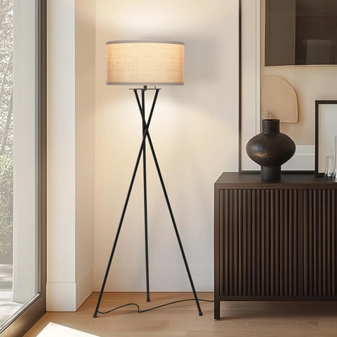 LED Floor Lamp Tall Tripod With Drum Shade In Black Finish And Gold Accents, next to a cabinet in a modern living room setting.