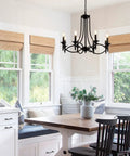 Industrial Candle Chandelier In Black Iron With Eight Lights hanging over a modern farmhouse dining area with a wooden table.