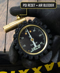 MBX 60 PSI Presta Tire Pressure Gauge for Bikes, Built for MTB and XC, Go To Portable with Shock Resistant Cover, ANSI B40.1 Calibrated for 1.5 Percent Accuracy, Trail Ready Gauge for Precise Mountain Bike Inflation, black-gloved hand holding gauge with brass valve