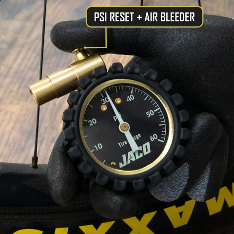 MBX 60 PSI Presta Tire Pressure Gauge for Bikes, Built for MTB and XC, Go To Portable with Shock Resistant Cover, ANSI B40.1 Calibrated for 1.5 Percent Accuracy, Trail Ready Gauge for Precise Mountain Bike Inflation, black-gloved hand holding gauge with brass valve
