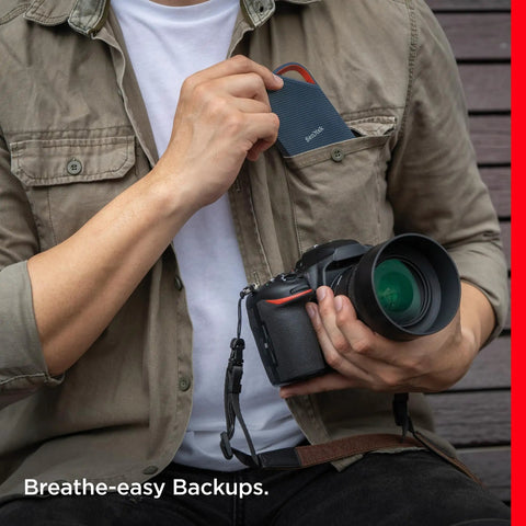 Photographer placing 4TB Extreme Pro Portable SSD With USB4 Speeds Up To 3800 MBps Read And 3700 MBps Write into pocket while holding camera