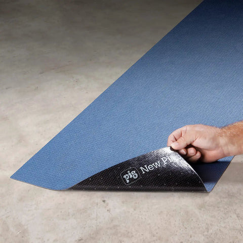 Person unrolling Adhesive-Backed Absorbent Mat For Industrial Floors, Grippy Surface That Stays Put, 16 W X 25 Ft L, Blue, Slip-Resistant.