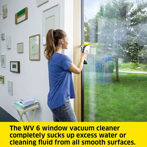 Side view of a woman using a white and black Kärcher WV 6 electric window vacuum squeegee on a glass door.
