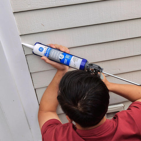 Person applying Clear Silicone Caulk Sealant For Indoor And Outdoor Use, 100 Percent Waterproof, Weatherproof And Flexible, on siding.