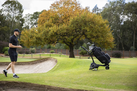 All Terrain Remote Controlled Electric Golf Caddy With Quick Zip Fold Setup Includes Drink Phone Umbrella Mounts Signature Power Bundle And Towel Keep It Smooth And Easy On The Daily on a golf course.