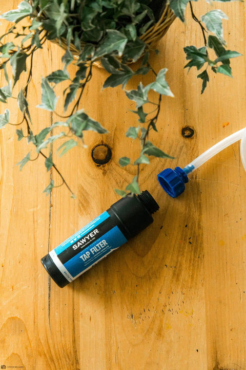 Tap Water Filtration System With 0.1 Micron Inline Filter, Fits Faucets And Hose Bibs, Blue filter next to plant on wooden table