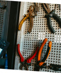 Assorted pliers hanging on perforated panel with tools nearby, ideal for use with 100 Pcs Plastic Hole Plugs White Screw Cap Covers.